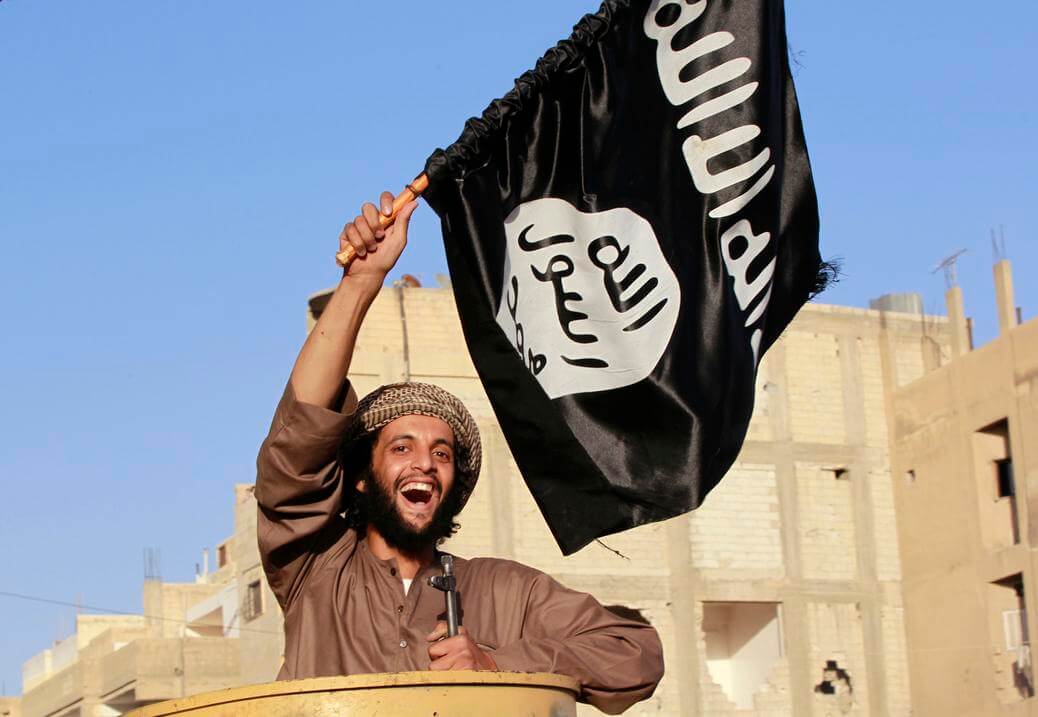 A militant Islamist fighter waving a flag, cheers as he takes part in a military parade along the streets of Syria's northern Raqqa province June 30, 2014. The fighters held the parade to celebrate their declaration of an Islamic "caliphate" after the group captured territory in neighbouring Iraq, a monitoring service said. The Islamic State, an al Qaeda offshoot previously known as Islamic State in Iraq and the Levant (ISIL), posted pictures online on Sunday of people waving black flags from cars and holding guns in the air, the SITE monitoring service said. Picture taken June 30, 2014. REUTERS/Stringer (SYRIA - Tags: POLITICS CIVIL UNREST CONFLICT) - RTR3WKMT