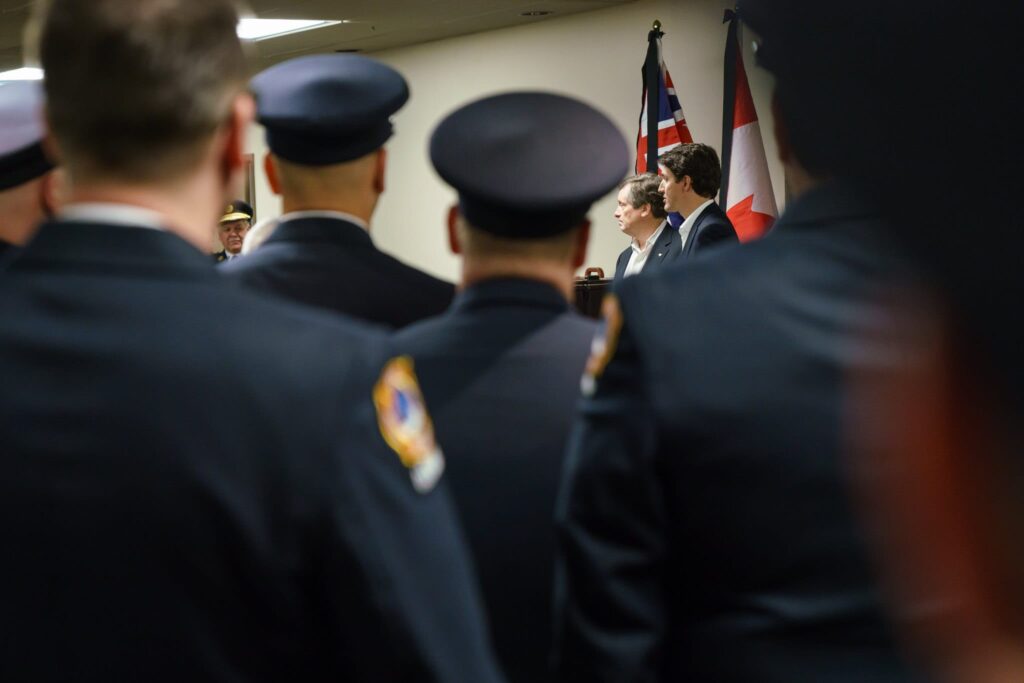 Police officers listen to a speaker at an indoor event with American flags.