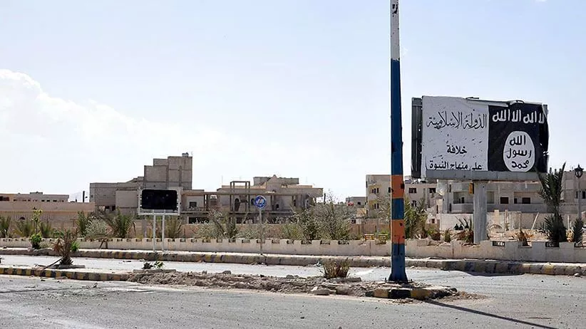 Deserted urban street with a tall pole and Arabic sign in the background.