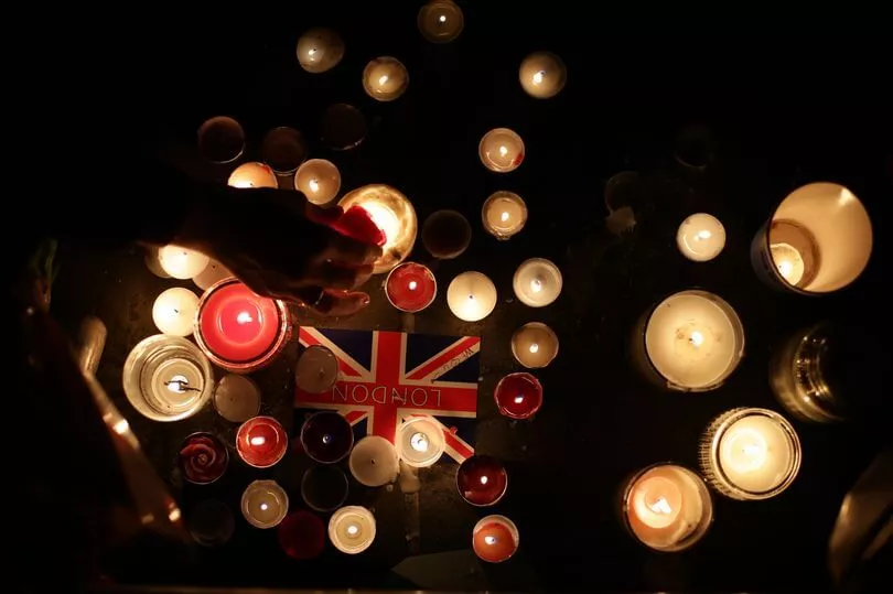 Candles and a British flag create a solemn tribute.