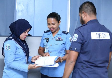 Three uniformed personnel reviewing documents in a discussion.