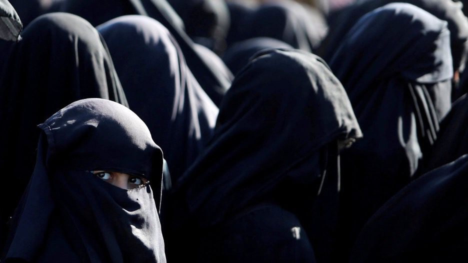 Group of people wearing black hooded clothing in close proximity.