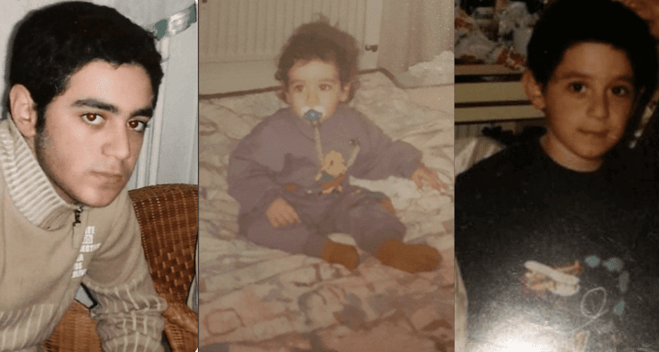 A toddler with a pacifier sitting on a blanket indoors.