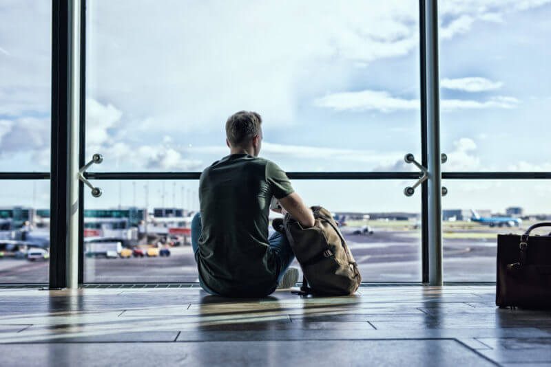 Man sitting with his dog at an airport window.