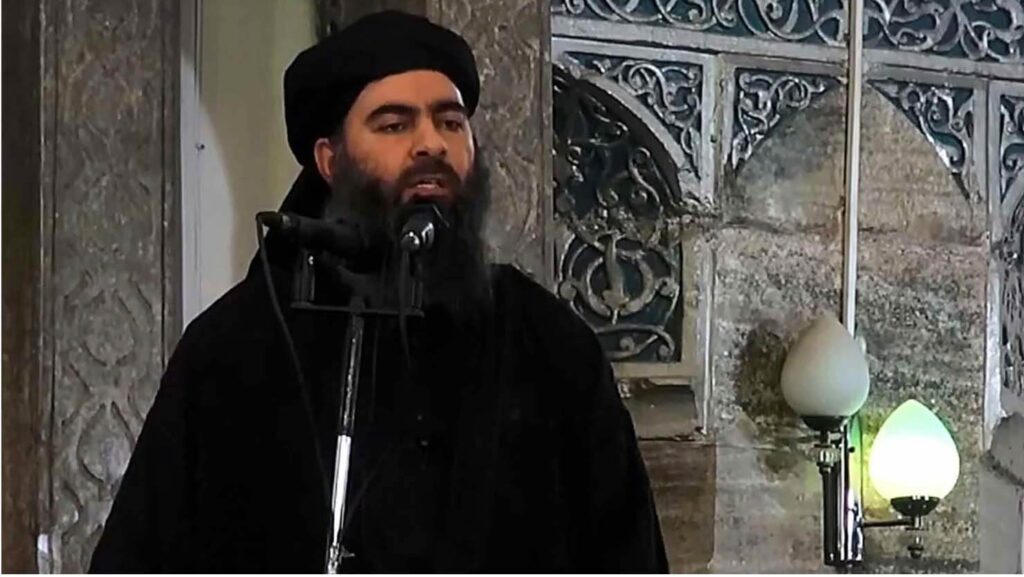 Man with black beard and turban speaking into a microphone.