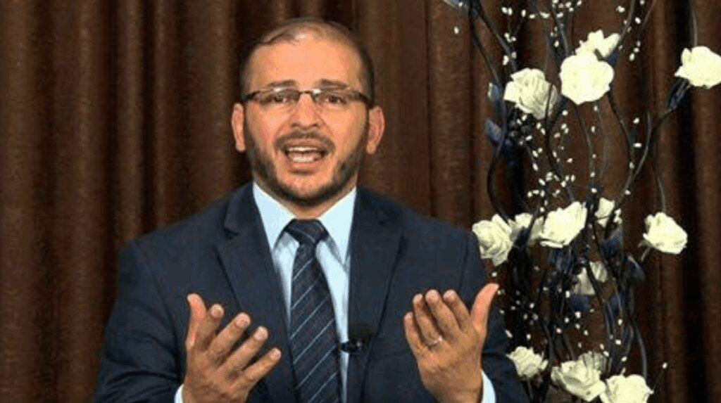 Man in suit speaking passionately with hands raised.
