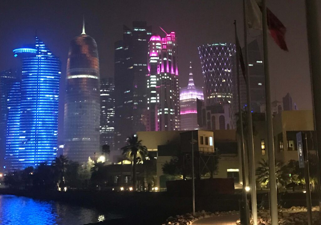 cropped-large-scaled City skyline illuminated with colorful lights at night.