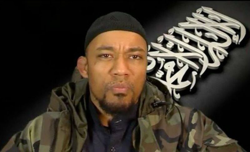 Man wearing a black cap and camouflage jacket with a serious expression.