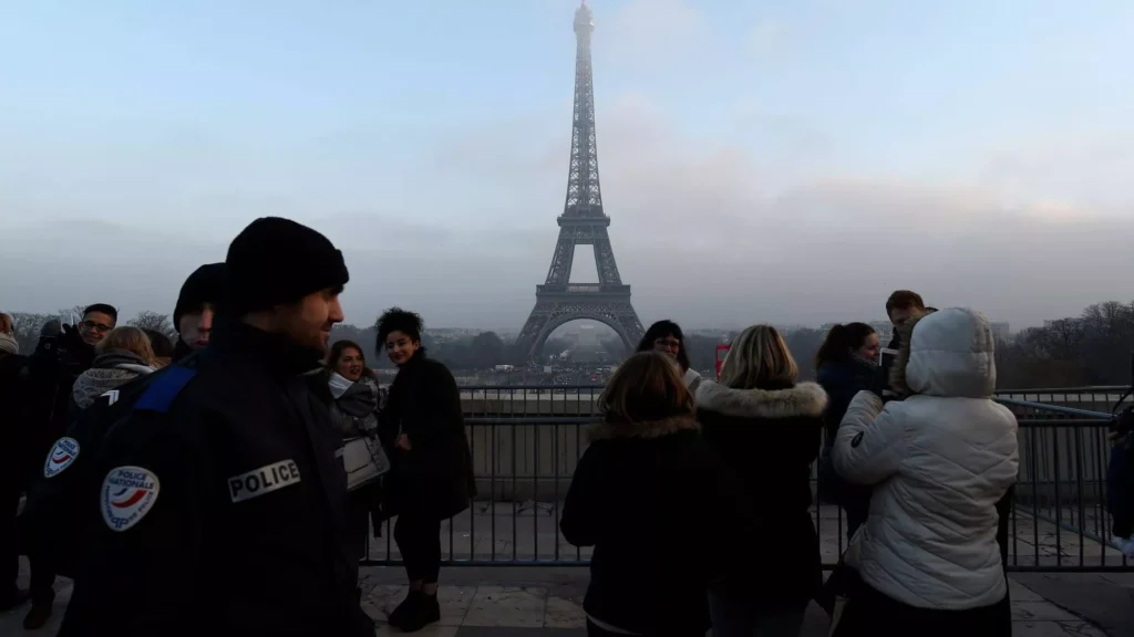 Tourists gather near the Eiffel Tower on a foggy day.