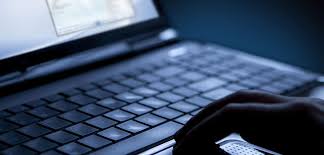 Close-up of a laptop keyboard with a hand on the mouse.