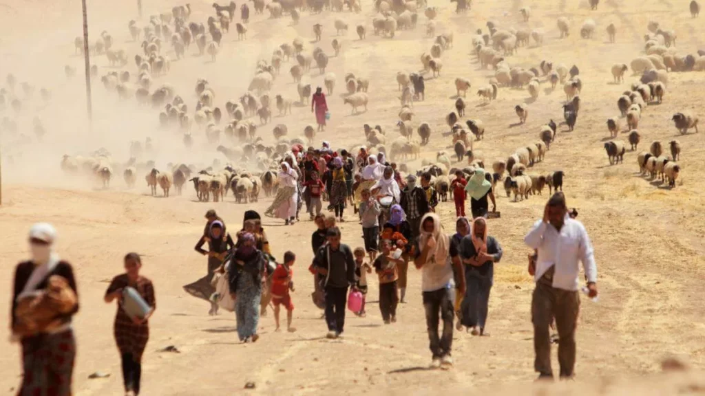 A large group of people walking through a dusty, arid landscape.