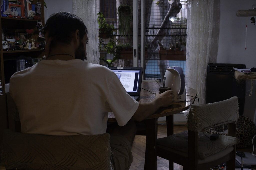 Person working on a laptop in a dimly lit room at night.