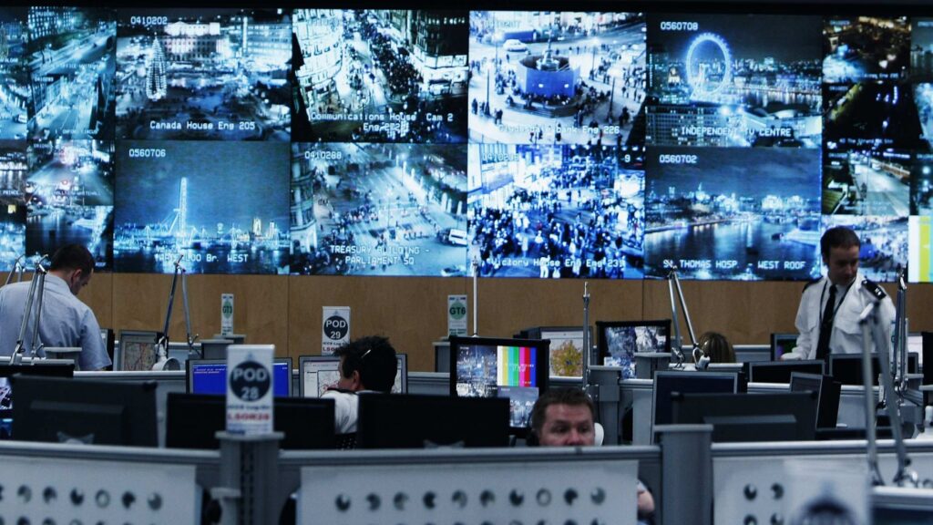 A busy control room with multiple monitors displaying surveillance footage.