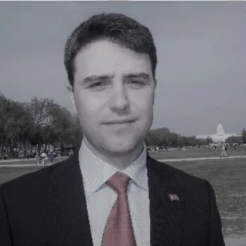 Picture1-350x350-2 Man in suit and tie outdoors with a blurred background.