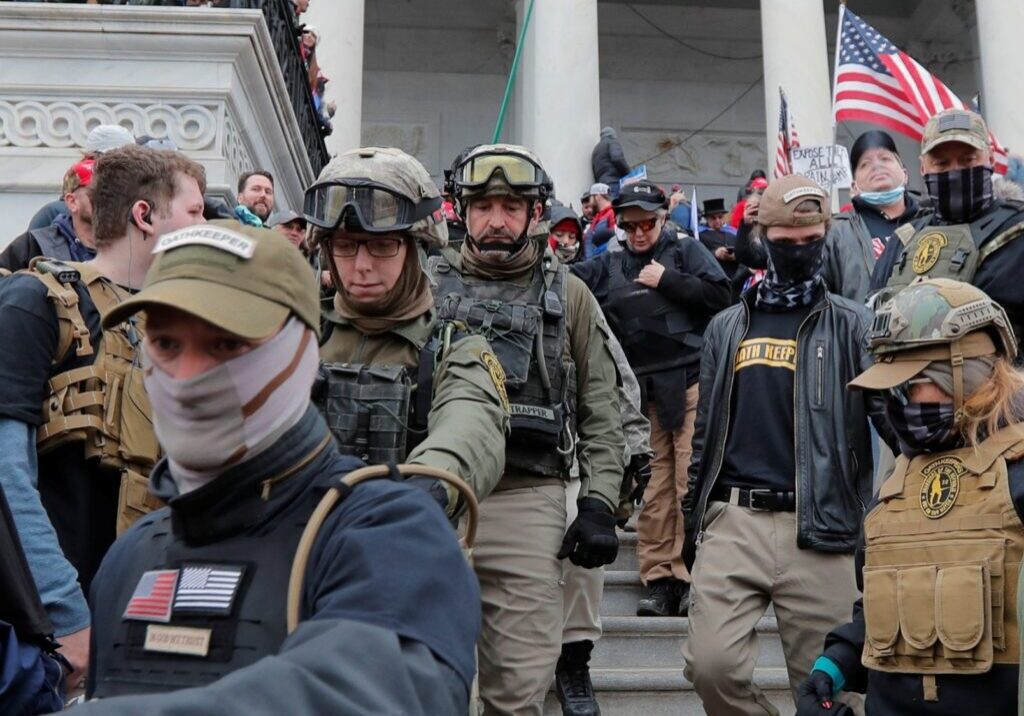 A group of armed law enforcement officers in tactical gear on stairs.