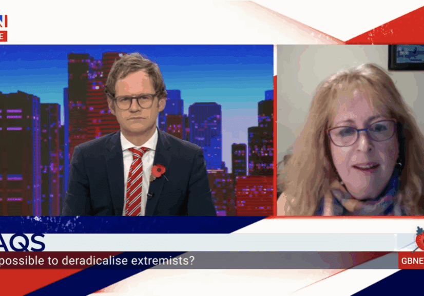 Two people engaged in a televised discussion with a cityscape background.