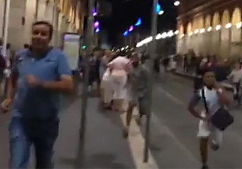 People walking on a lively, illuminated city street at night.