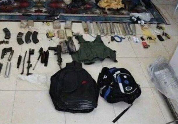 Various weapons, body armor, and bags laid out on the floor.