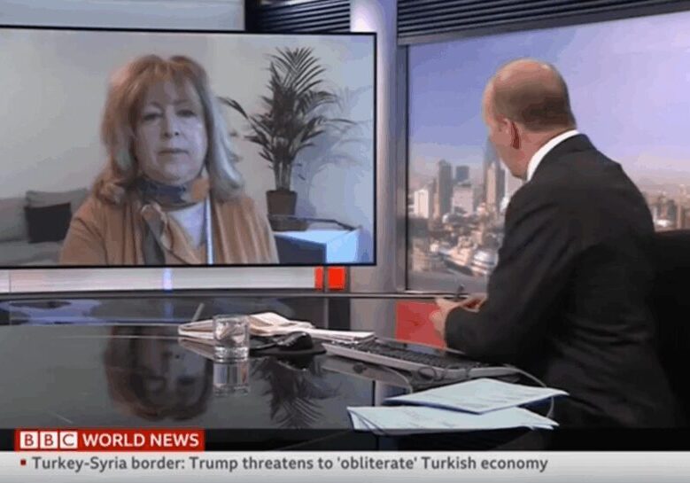 A news anchor interviews a guest via video call on a news channel.
