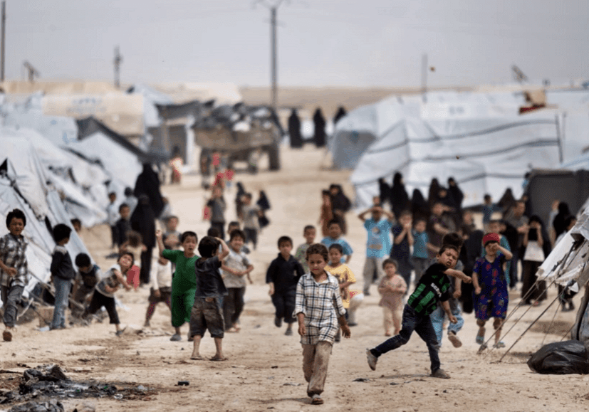 Children walk and play near tents in a refugee camp.