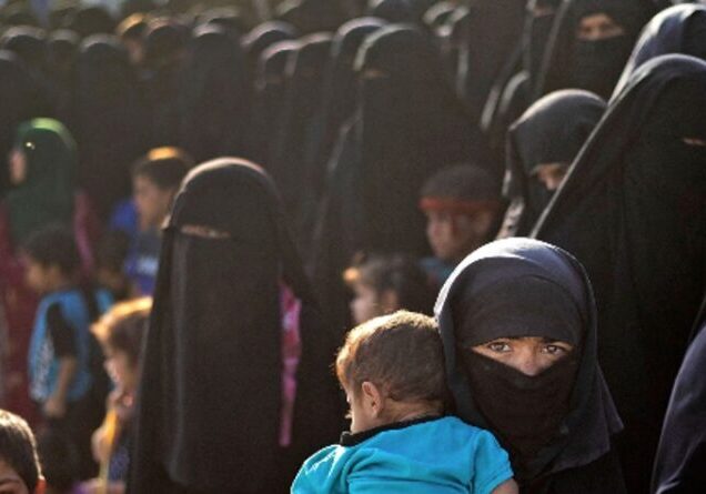 Women in black niqabs with children in a crowded outdoor setting.