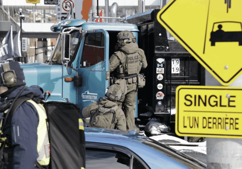 A SWAT team member stands near a police vehicle during an active situation.